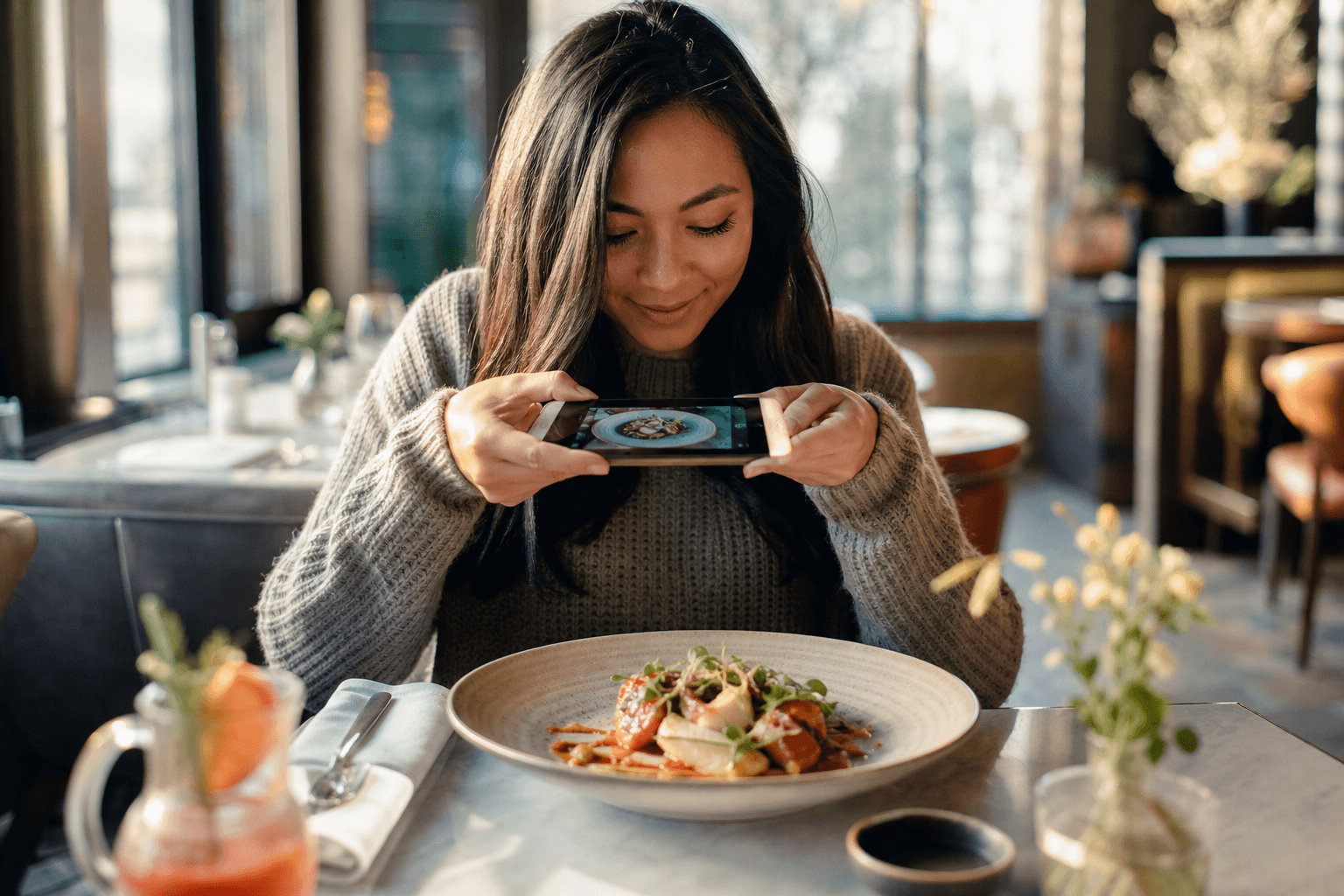 A guest photographing a beautifully plated dish with a phone